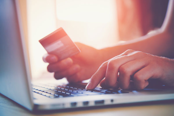 A Photograph of a Laptop and an Indivdiuals Hands Holding a Credit Card