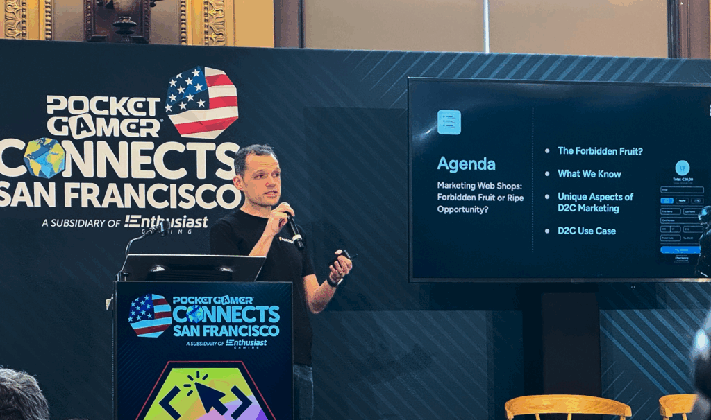 Chip speaks into a microphone in front of a dark blue backdrop while presenting at PGC 2025.