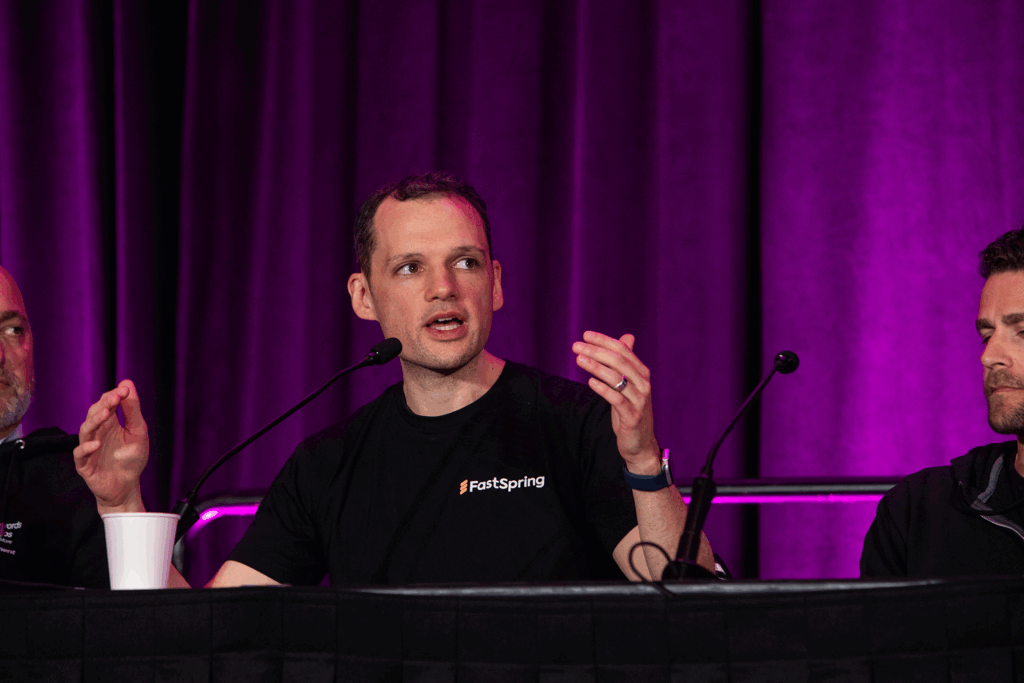 Chip speaks into a table microphone and gesticulates with both hands up.