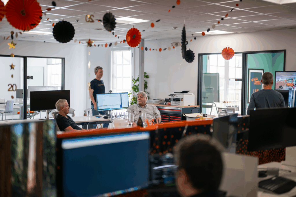 A bright office space with black and orange decor and a few people.