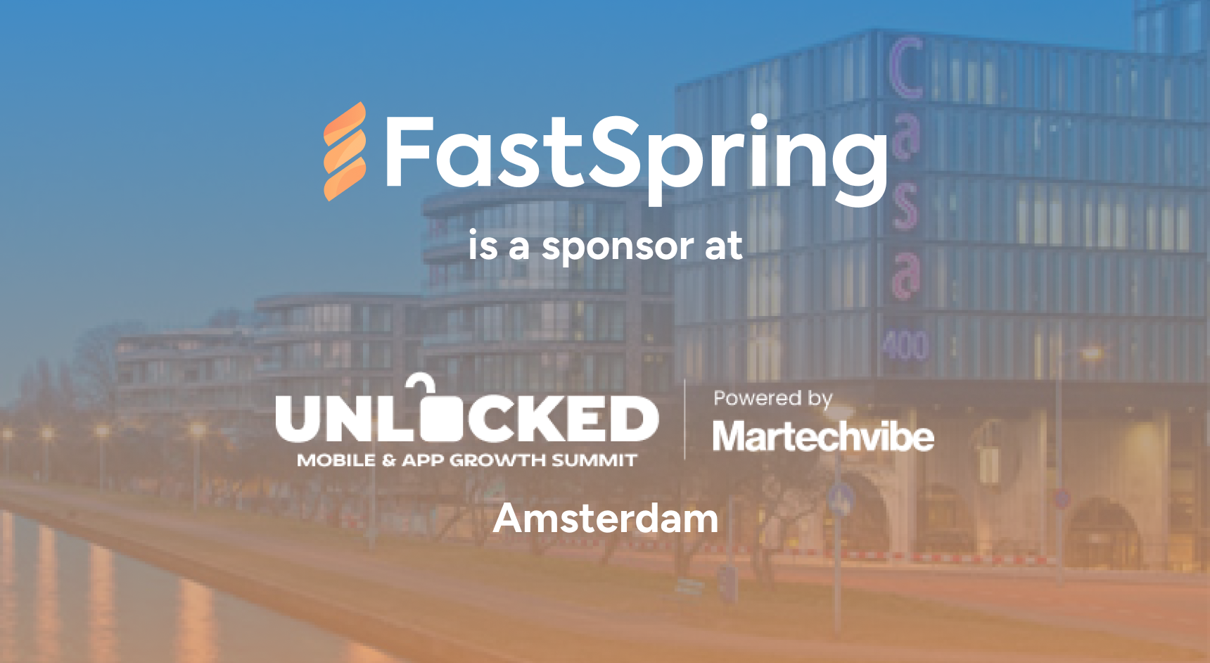 An orange and white FastSpring logo and a white Unlocked logo, both over a blue-to-orange gradient image of Amsterdam.