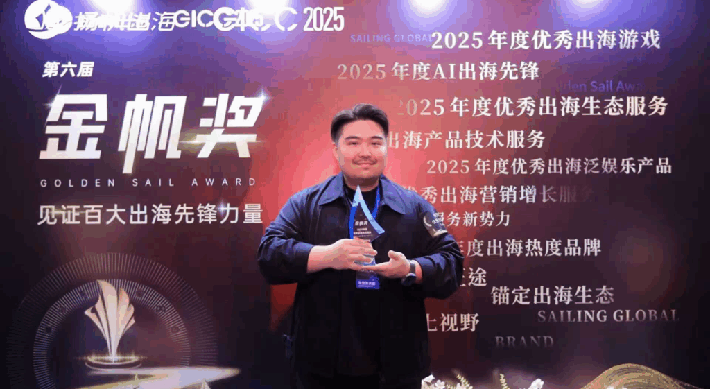 A photo of a man holding a glass trophy in front of a colorful backdrop covered with Chinese writing.