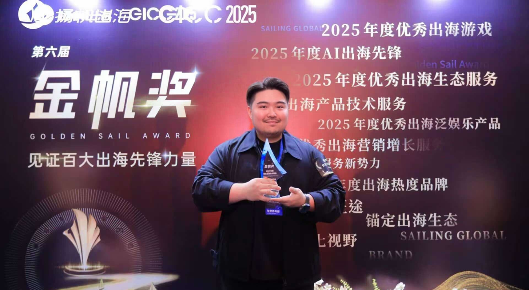 A photo of a man holding a glass trophy in front of a colorful backdrop covered with Chinese writing.