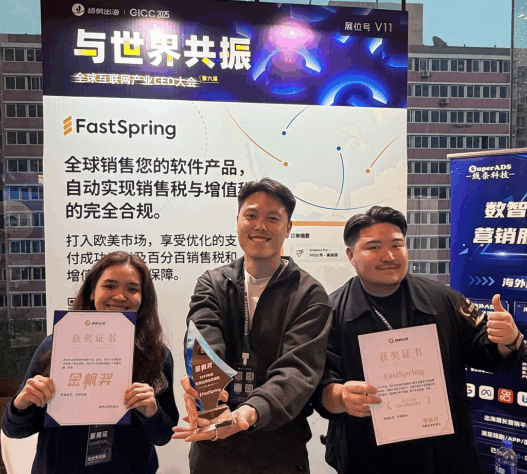 Three people standing in front of a blue and white FastSpring backdrop, each holding a certificate or trophy.